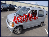 a silver car in a parking lot with a reserved sign