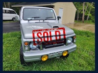 a silver suzuki samurai with a sold sign on it